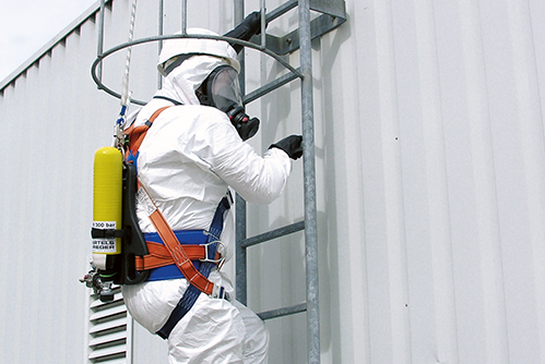 Arbeiter unter Atemschutzausrüstung klettert an Gebäude hoch